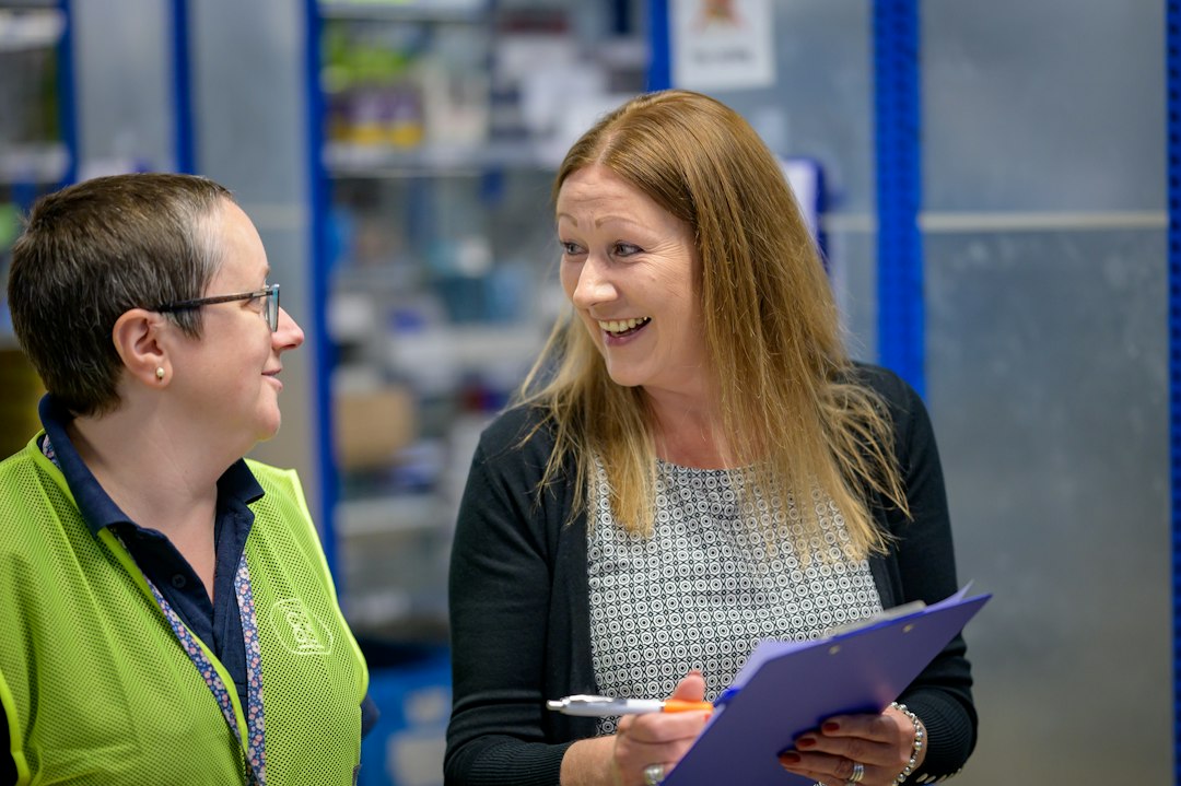 Two colleagues reviewing work in a warehouse